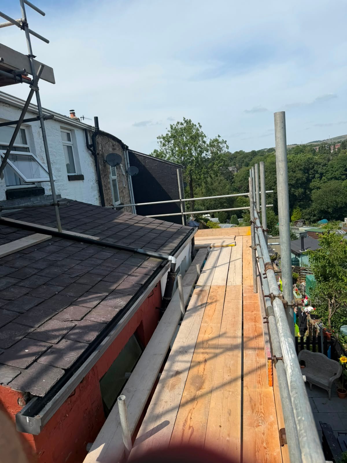 Roof edge scaffold platform with boarded access and guardrails