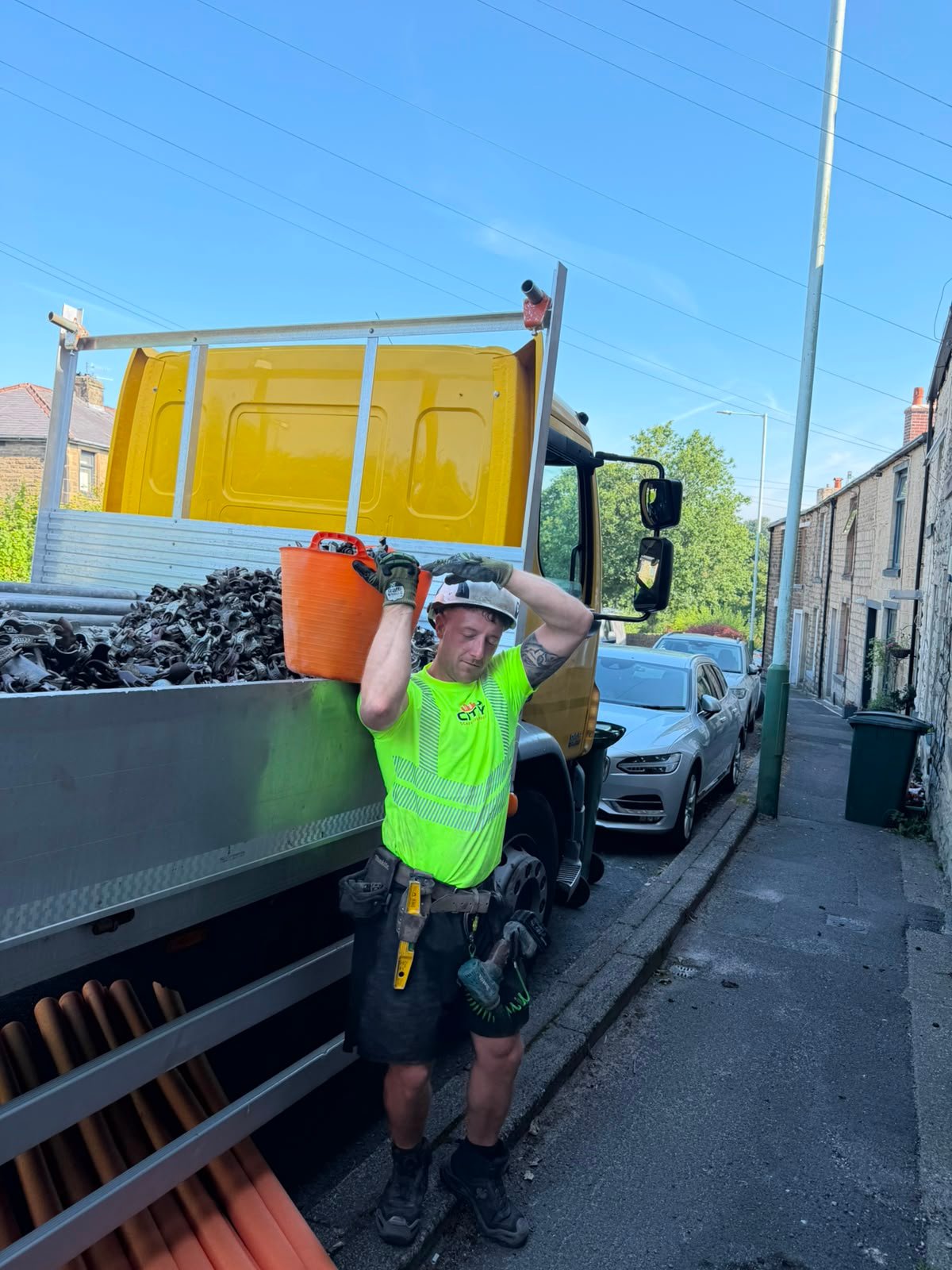City Scaffolding team member in branded high visibility uniform loading materials beside the company vehicle in Middleton, Manchester